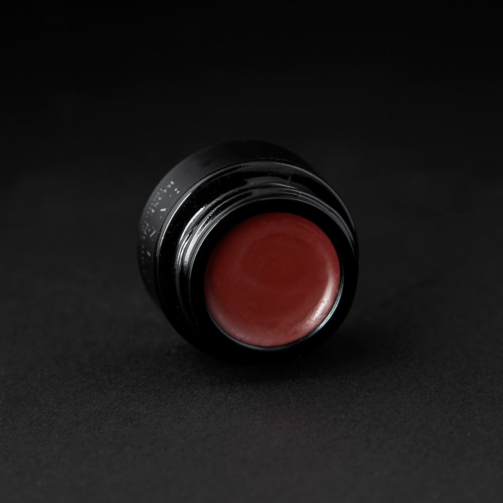 
                      
                        A deep, rosy blush coloured lip balm in a black glass pot on black background
                      
                    