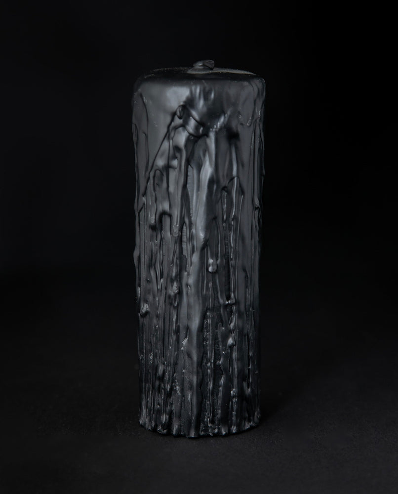 Black beeswax pillar candle by RITUAALIA with label removed, revealing the candle's rustic textured finish.